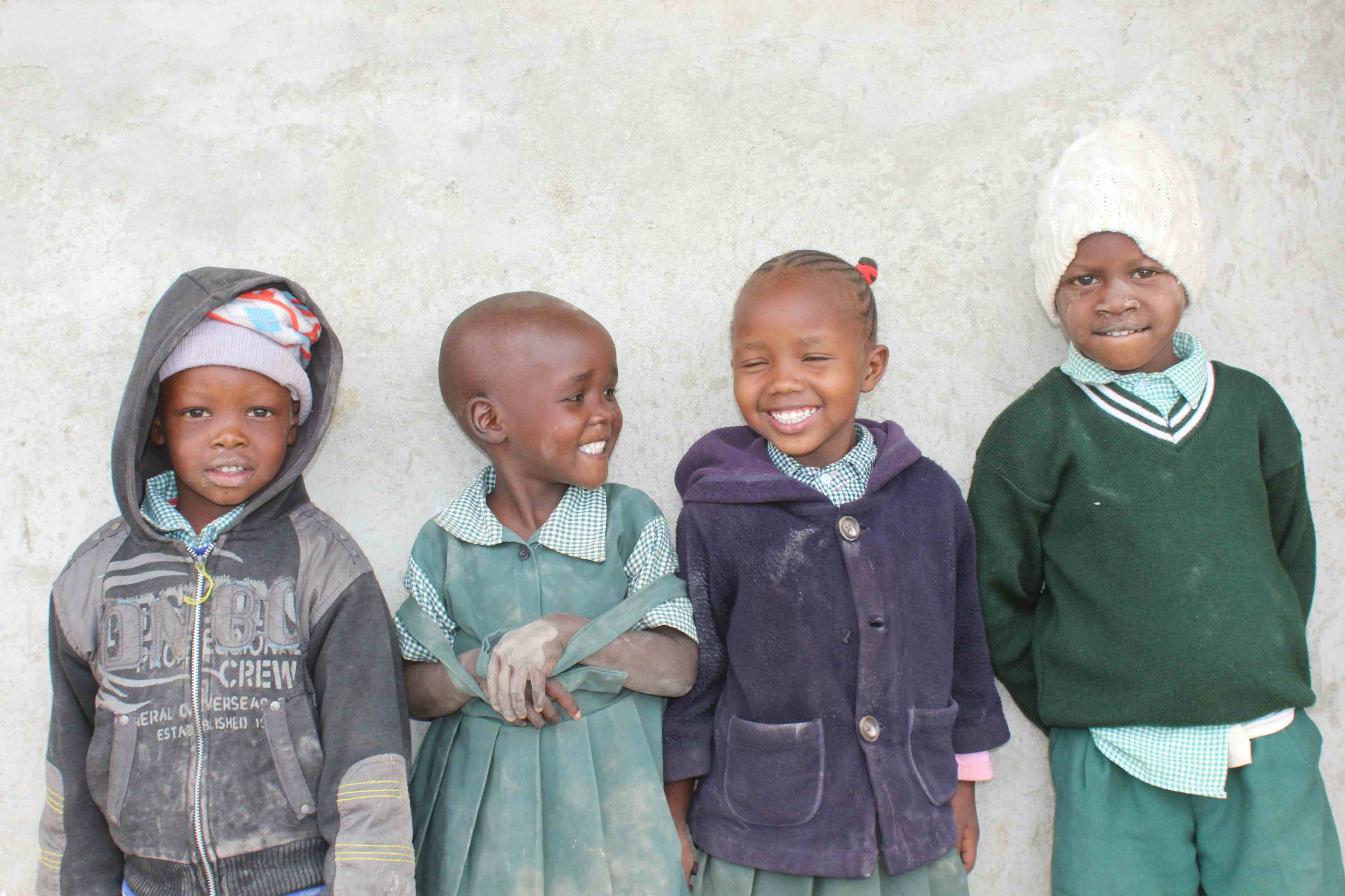 Four children in Kenya smiling outside computer class with TechLit Africa, at Zawadi Yetu.