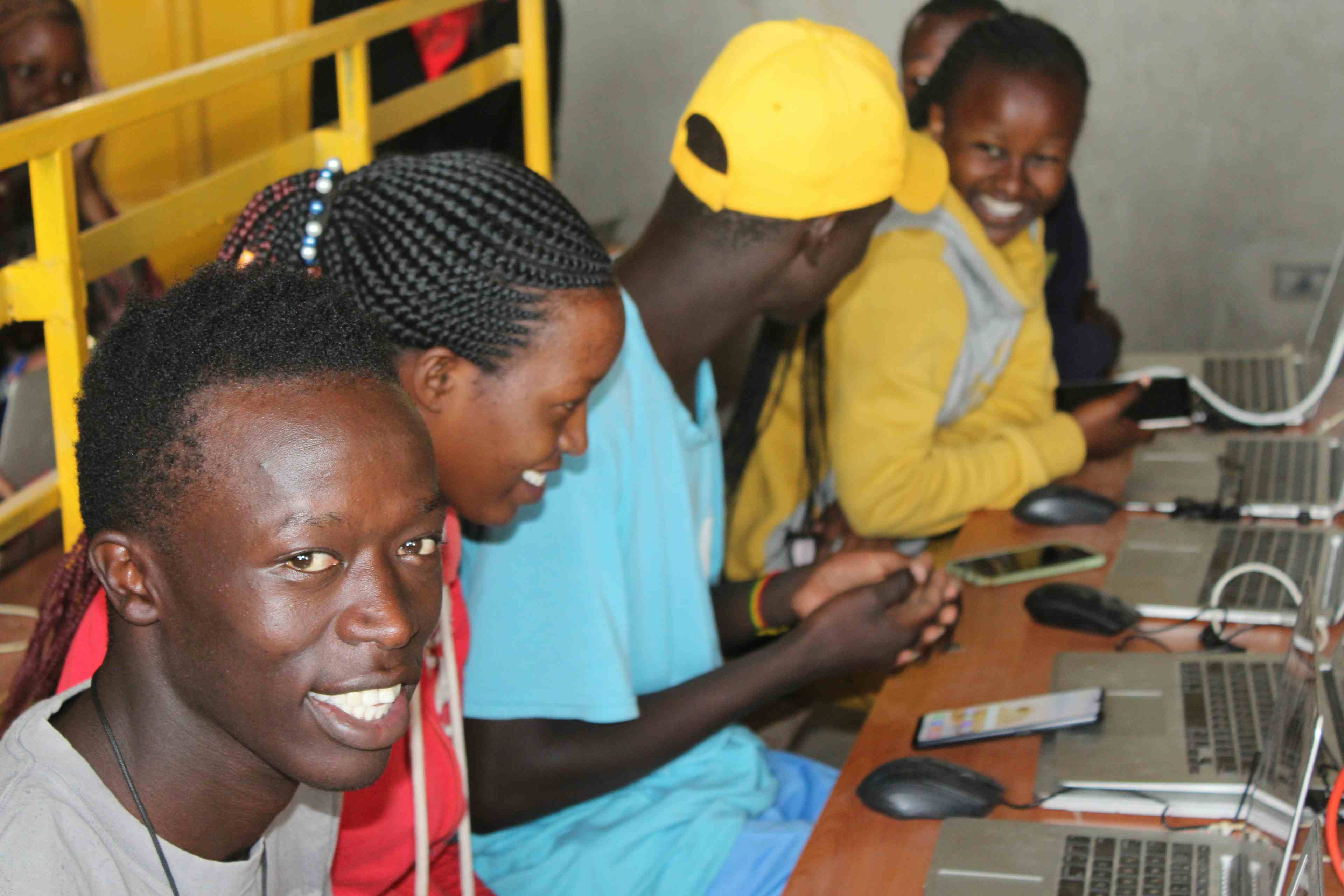 Kenya youth smiling with phones, laptops and mice