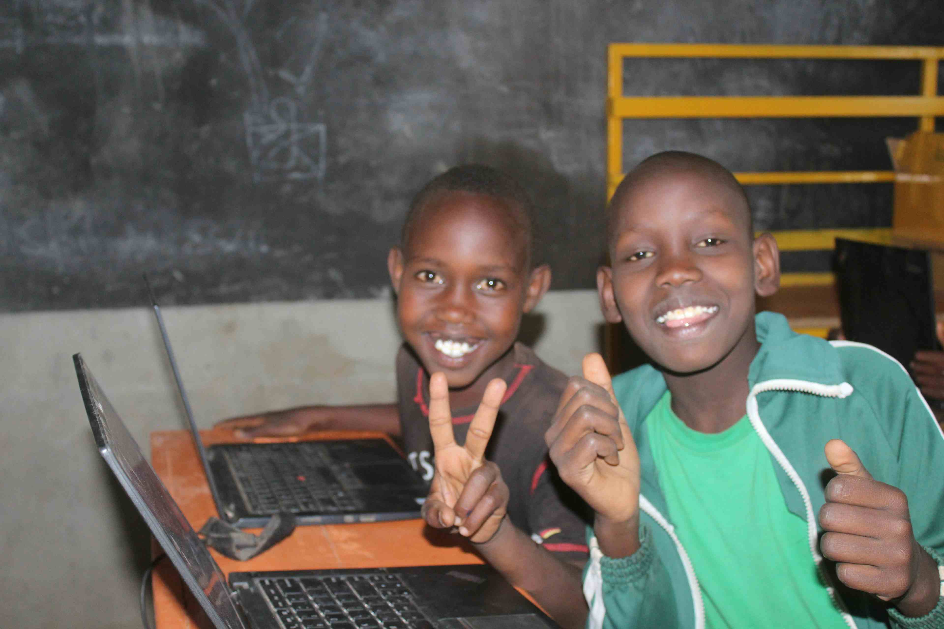 Bowen and Sammy students at Zawadi Yetu  sitting on desks at the TechLit Hub