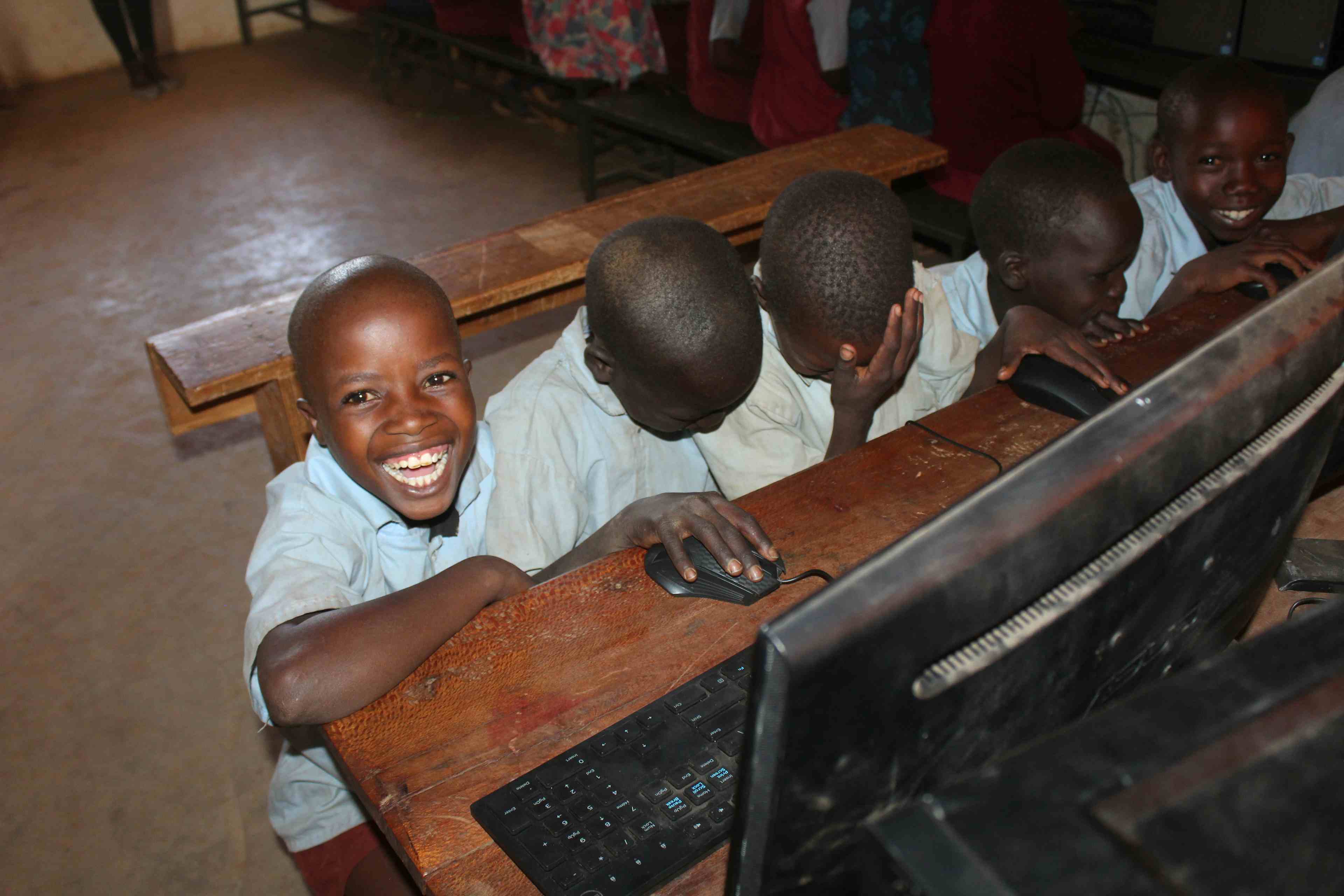 Students smiling with computers in primary school computer classroom