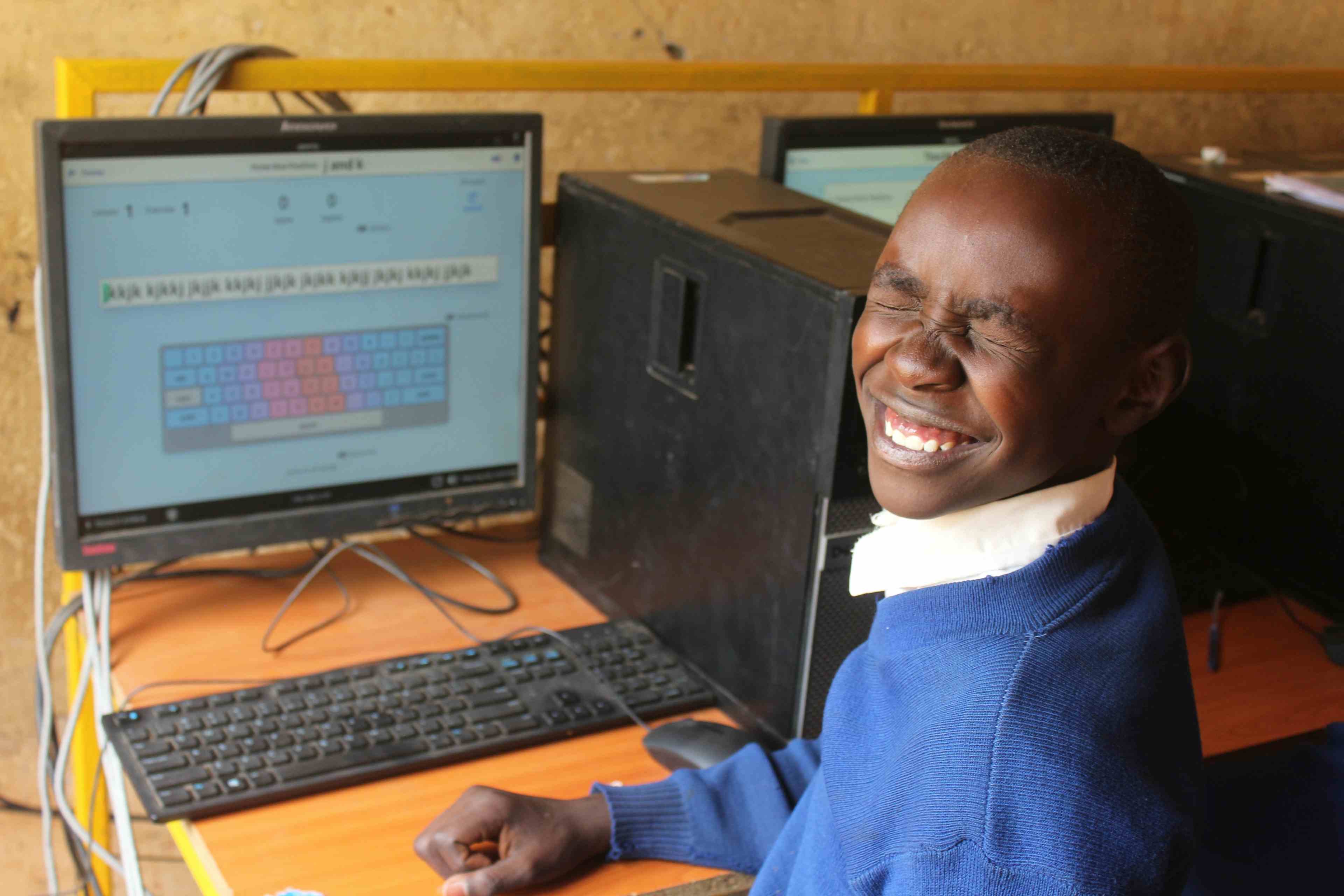 Student with Eyes Closed  at a computer lab in Mogotio Primary with QWERTY on screen