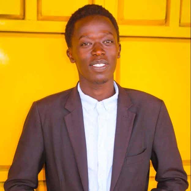 Portrait of Allan Kiprono in a suit by a yellow door
